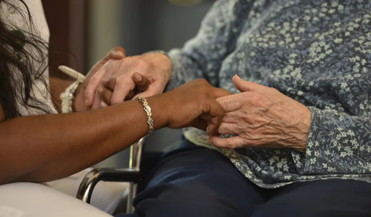 Nurse hands holding a senior womans hands
