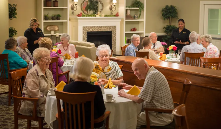 A full dining room with smiling residents enjoying a meal