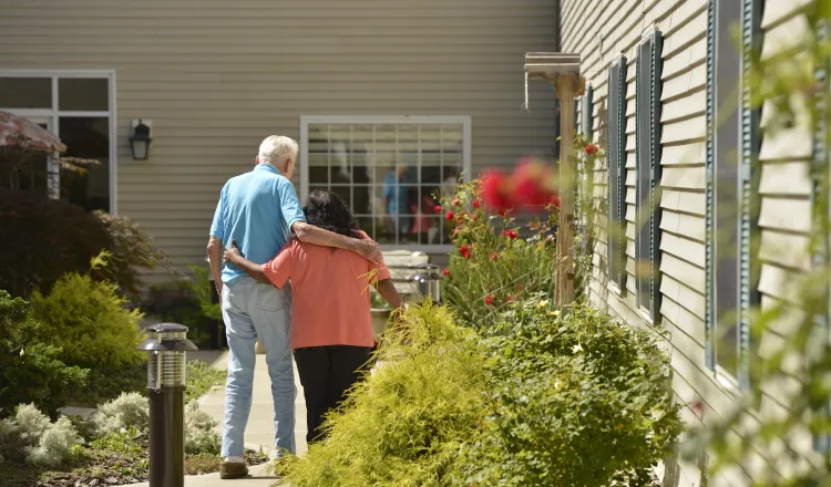 A staff member and a resident take a stroll through the gardens