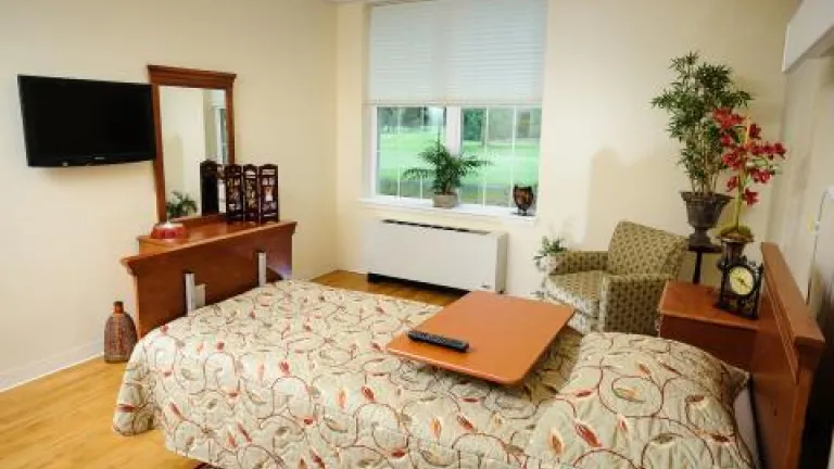 A private room with a twin bed, armchair, and vanity in Kingsway Arms