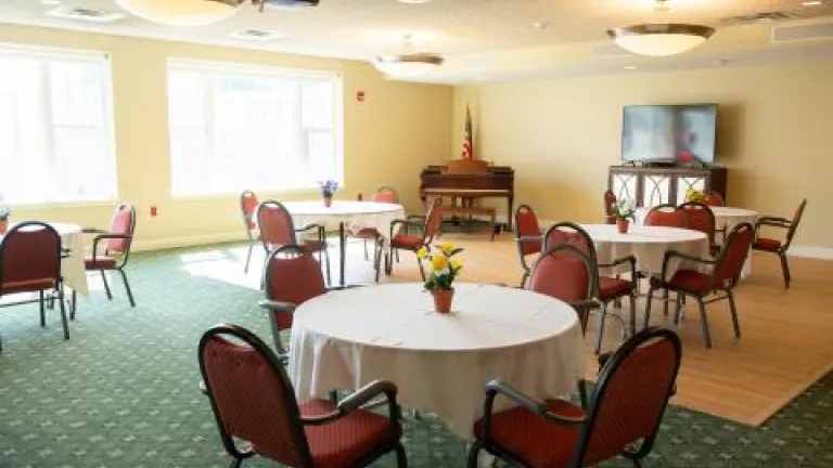 Kingsway Manor's Activity Room, with green carpeting and several four-person tables with white table cloths