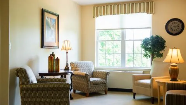 A cream-colored living room with green-patterned arm chairs