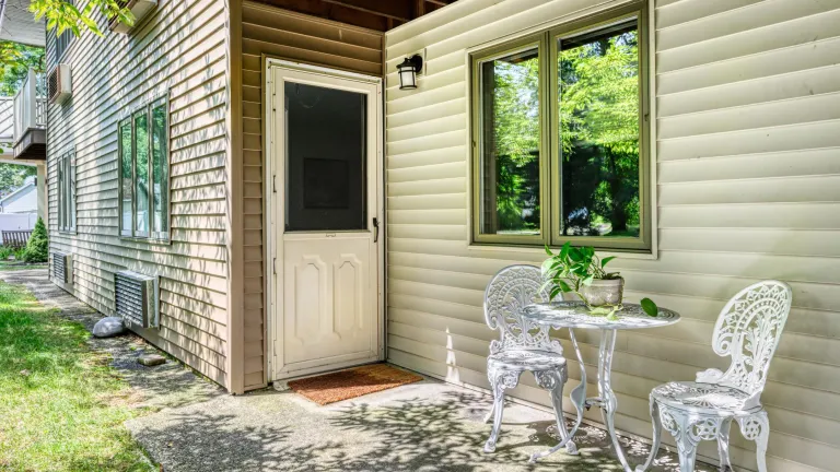 A back patio outside a screened back door, with white metal patio furniture