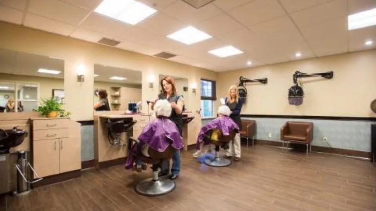 Two women in purple smocks getting their hair done at the salon