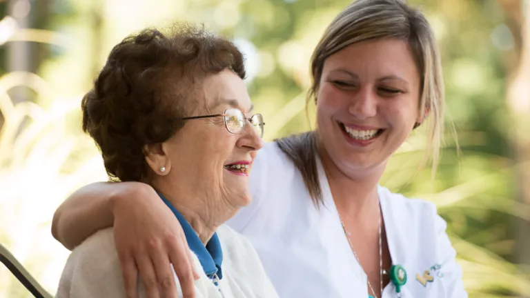 An employee sitting on a bench with an elderly resident