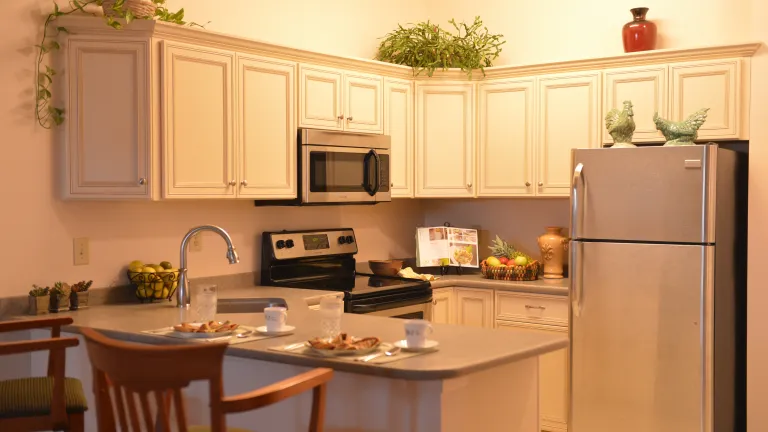 A kitchen with white cabinets, gray countertops, and stainless steel appliances