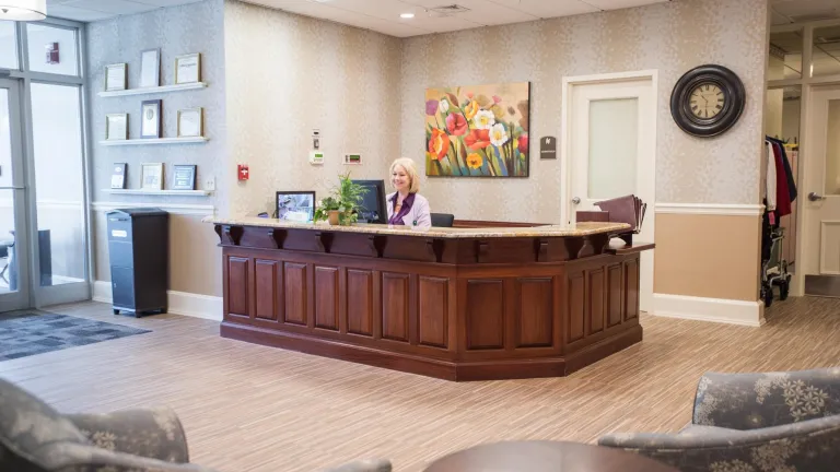 A woman seated behind a receptionist desk in the main lobby of Kingsway Arms