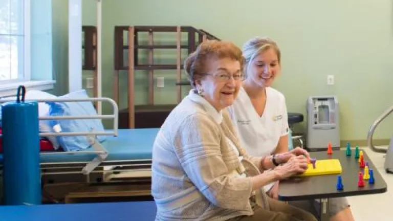 A resident and nurse seated and doing dexterity exercises