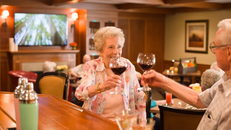 A woman and man toasting at a bar with red wine