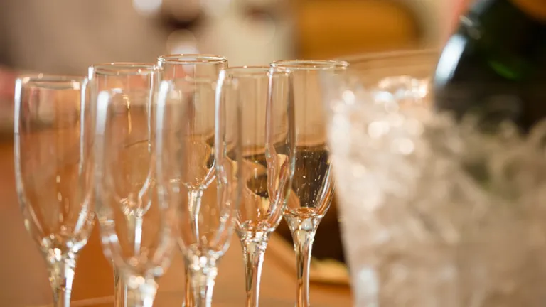 A bottle of champagne on ice and champagne flutes
