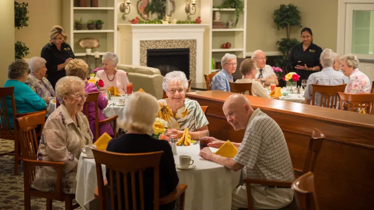 A full dining room with smiling residents enjoying a meal