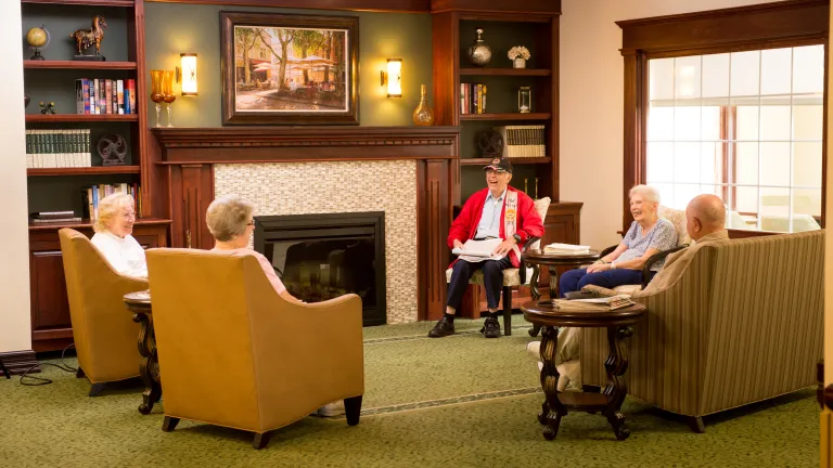 Five people seated around a fire place in the Kingsway Manor main lobby