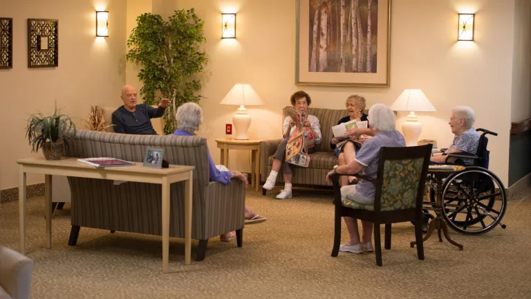 Six people, one in a wheelchair, sitting chatting in a lounge at Kingsway Manor