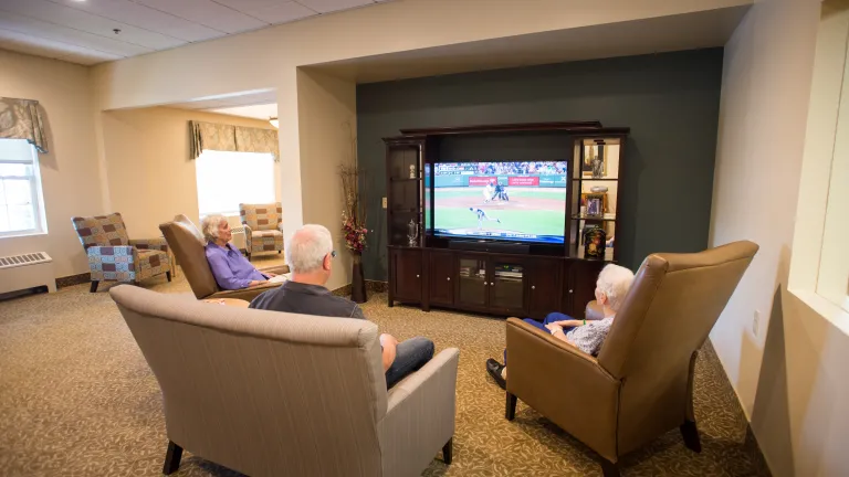 Three residents watching a baseball game in comfy chairs