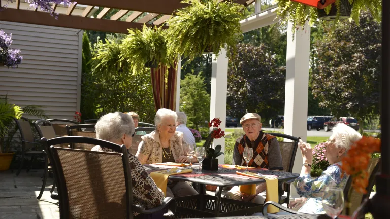 Group of Kingsway residents sitting at a table outdoors on a sunny day