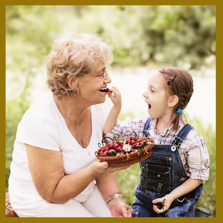 Older woman eating fruit outside with granddaughter