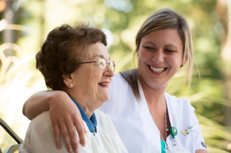 An employee sitting on a bench with an elderly resident