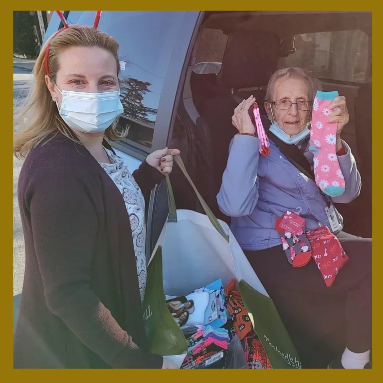 Kingsway staff member and resident hold up socks for camera