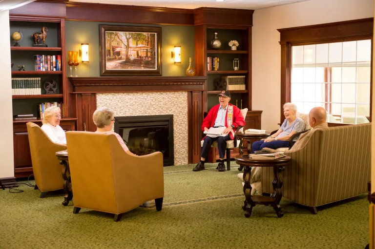 Five people seated around a fire place in the Kingsway Manor main lobby