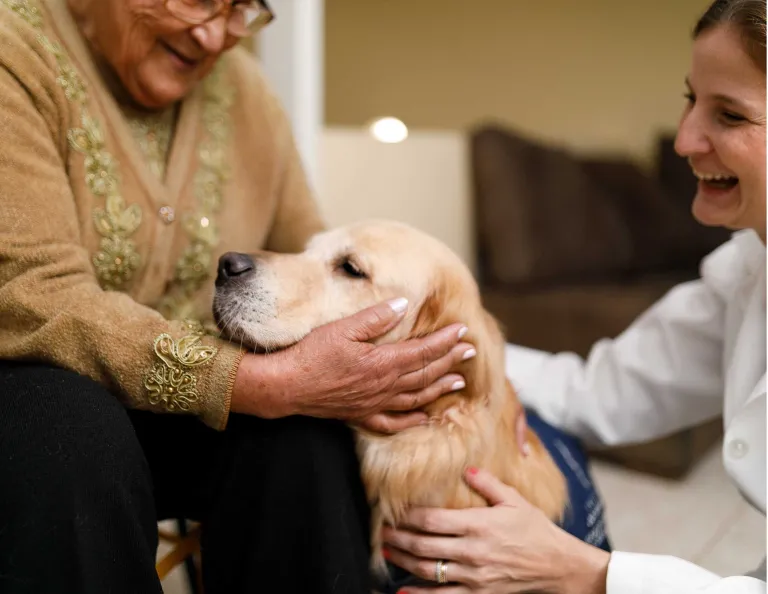 A resident with a therapy dog and its handler.