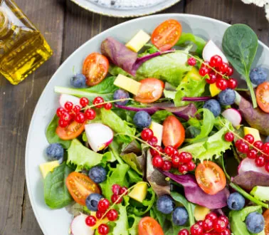Fresh green salad with diced tomatoes, blueberries and radishes