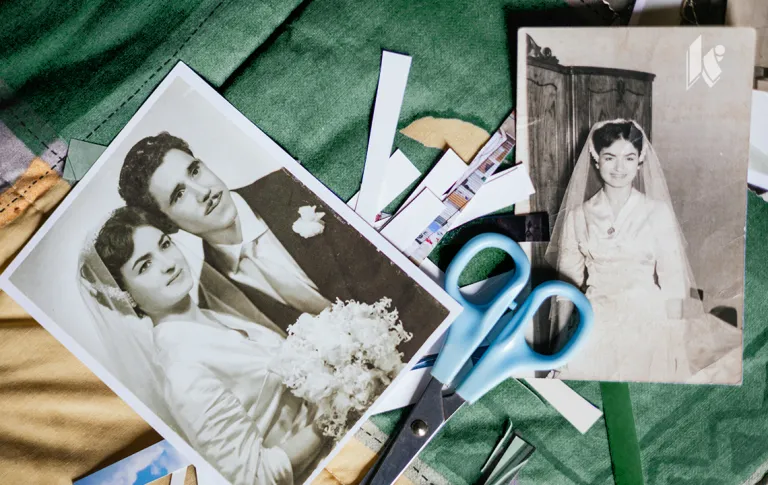 A flat lay on green and gold fabric with a few black and white images and a pair of scissors, scraps from cut photos can be seen under the scissors