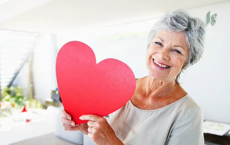 Senior woman holds giant paper heart