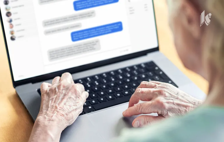 A senior woman uses a laptop, the screen is faded but you can see a message thread back and forth.