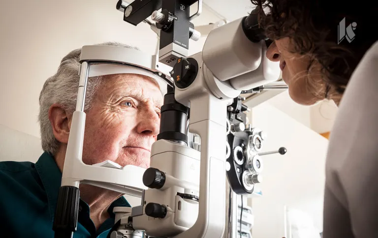 A senior male sits for an optometrist during an eye exam 