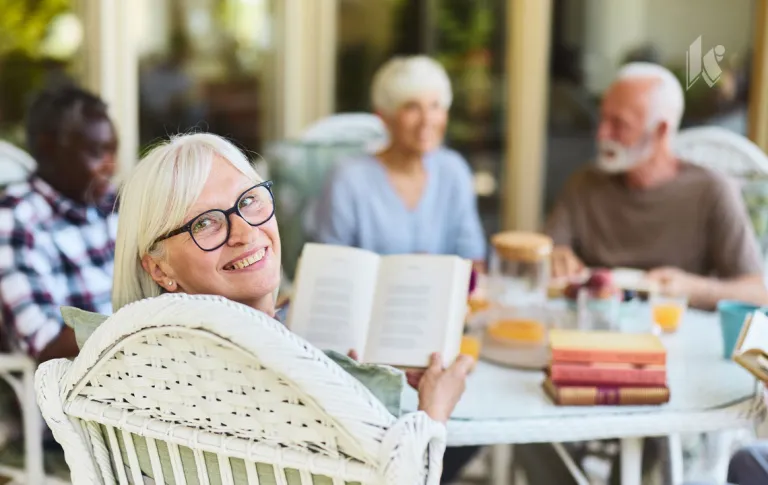Seniors sitting around a table reading books and talking over lunch